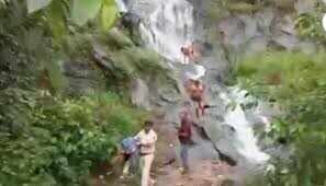 அருவியில் குளித்த சுற்றுலா பயணிகளின் துணிகளை எடுத்துச்சென்ற போலீஸ்